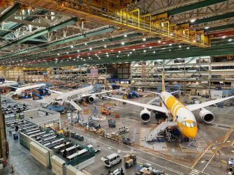 View of a Boeing production plant with multiple aircraft in various stages of assembly and workstations.