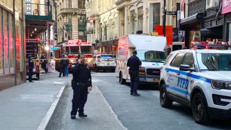 Emergency responders at the scene of the Manhattan parking garage collapse, with police and fire vehicles present.