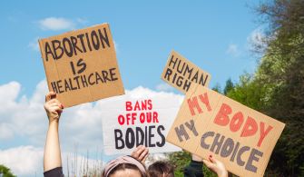 Protesters holding signs advocating for abortion rights, including messages about healthcare and bodily autonomy.