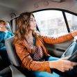A ride-share driver navigating the streets while a passenger uses a phone in the back seat. A ride-share driver navigating the streets while a passenger uses a phone in the back seat.