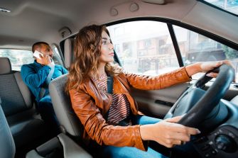 A ride-share driver navigating the streets while a passenger uses a phone in the back seat.