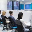 A row of customer service representatives wearing headsets, seated in cubicles at a call center. A row of customer service representatives wearing headsets, seated in cubicles at a call center.