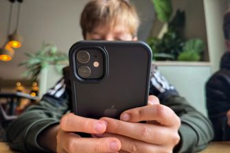 A young person holding a smartphone, likely engaging with online content.