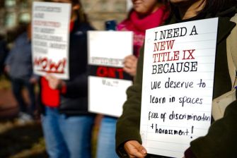 Students holding signs during a protest advocating for a new Title IX to ensure learning environments free from discrimination and harassment.