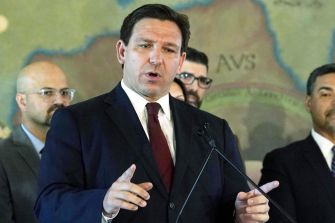 Florida Governor Ron DeSantis speaking at a press conference about Senate Bill 1808, which mandates law enforcement to collaborate with ICE on immigration enforcement.