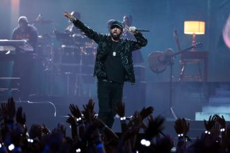 Eminem performing on stage with an enthusiastic audience in the foreground.