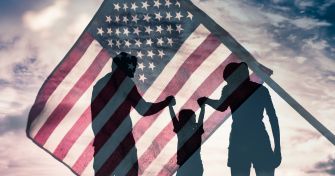 Silhouette of a family holding hands in front of an American flag.
