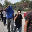 Group of individuals walking along a street, some with their faces obscured. Group of individuals walking along a street, some with their faces obscured.