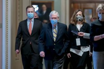 Mitch McConnell and aides walking in the U.S. Capitol wearing masks.