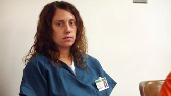 Image of a woman in custody attire sitting in a courtroom.