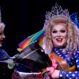 Drag performers celebrating during a performance, with one holding flowers and wearing a colorful outfit. Drag performers celebrating during a performance, with one holding flowers and wearing a colorful outfit.