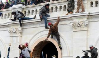 A group of individuals climbing onto the Capitol building during the January 6th riot.
