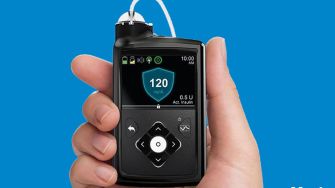 Image of a Medtronic MiniMed 630G insulin pump held in a hand, displaying its screen interface.