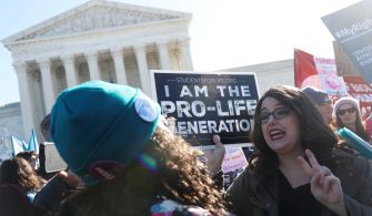 Pro-life demonstrators outside the Supreme Court holding signs advocating against abortion rights.