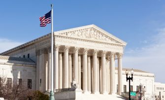 The United States Supreme Court building with an American flag flying in front.
