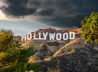 The iconic Hollywood sign surrounded by hills and trees under a dramatic sky.