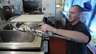 A man working in an ice cream shop, handling equipment.