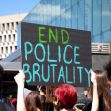Sign at a protest reading "END POLICE BRUTALITY" with participants in the background. Sign at a protest reading "END POLICE BRUTALITY" with participants in the background.
