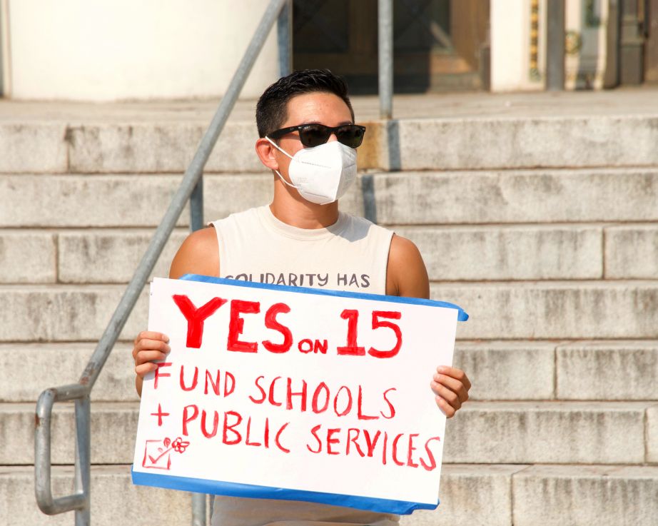 Man holding sign Yes on 15 Fund Schools and Public Services