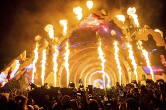 A vibrant concert scene featuring flames and a colorful stage backdrop, capturing the atmosphere of a live music festival.