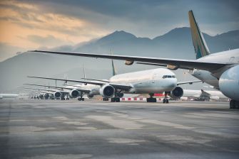 A row of airplanes parked on a runway with mountains in the background.