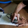 A person using a medical device to check their blood oxygen levels, surrounded by paperwork and a tablet displaying health information. A person using a medical device to check their blood oxygen levels, surrounded by paperwork and a tablet displaying health information.