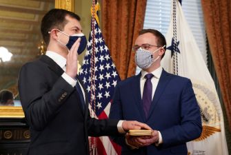 Pete Buttigieg being sworn in as Secretary of Transportation, holding a book while taking the oath of office.