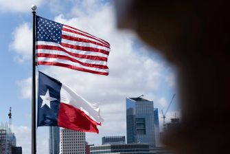 Image of the U.S. and Texas flags flying in front of a city skyline.