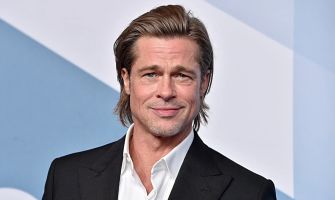 Brad Pitt smiling at a public event, wearing a black suit.