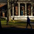 Two students walking on Harvard University's campus, with a historic building featuring columns in the background. Two students walking on Harvard University's campus, with a historic building featuring columns in the background.