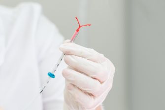 A medical professional holding an Essure intrauterine device (IUD) for demonstration.