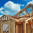 Under-construction tiny home with exposed wooden framing against a cloudy blue sky. Under-construction tiny home with exposed wooden framing against a cloudy blue sky.