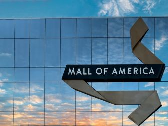 Signage of the Mall of America against a backdrop of cloudy skies at sunset.