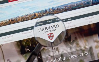 A magnifying glass focusing on the Harvard University logo displayed on a website.