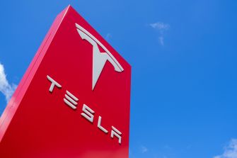 Tesla logo on a sign against a blue sky.