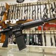 A display of firearms, including a prominent rifle in the foreground, at a gun shop. A display of firearms, including a prominent rifle in the foreground, at a gun shop.