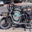 A close-up of electric bikes parked in an urban setting, featuring a prominent logo on one of the bikes. A close-up of electric bikes parked in an urban setting, featuring a prominent logo on one of the bikes.