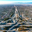 Aerial view of a sprawling highway system with traffic and a city skyline in the background. Aerial view of a sprawling highway system with traffic and a city skyline in the background.