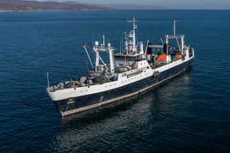 A large fishing vessel operating in open waters, with equipment and gear visible on deck.