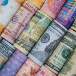 Various rolled banknotes from different currencies laid out in a row. Various rolled banknotes from different currencies laid out in a row.