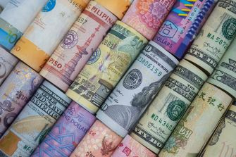 Various rolled banknotes from different currencies laid out in a row.