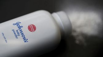 Container of Johnson's baby powder with a dusting of powder on a surface.