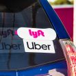 A close-up of the back of a car displaying both Uber and Lyft stickers. A close-up of the back of a car displaying both Uber and Lyft stickers.