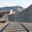 View of the border wall in a landscape setting, showcasing the structure's height and surrounding terrain. View of the border wall in a landscape setting, showcasing the structure's height and surrounding terrain.