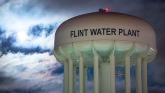 Flint Water Plant water tower illuminated at night, with clouds in the background.