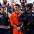 Suspect Luigi Mangione in handcuffs, wearing an orange jumpsuit, surrounded by law enforcement officers during his court appearance. Suspect Luigi Mangione in handcuffs, wearing an orange jumpsuit, surrounded by law enforcement officers during his court appearance.