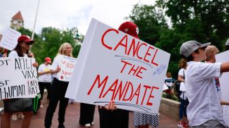 A group of protesters hold signs opposing the COVID-19 vaccination mandate at Indiana University.