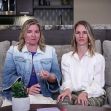 Two women seated on a couch, discussing their work or experiences, with a plant and table in front of them. Two women seated on a couch, discussing their work or experiences, with a plant and table in front of them.