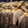 A group of boys in uniform and hats standing in line, with some wearing yellow neckerchiefs. A group of boys in uniform and hats standing in line, with some wearing yellow neckerchiefs.