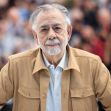 Francis Ford Coppola poses for a photo at a public event, wearing a beige jacket and standing in front of a blurred crowd. Francis Ford Coppola poses for a photo at a public event, wearing a beige jacket and standing in front of a blurred crowd.